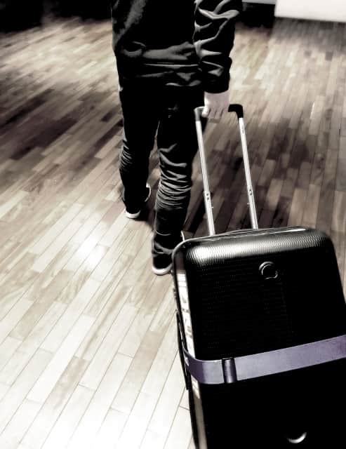 モノクロのスーツケースを引く男性