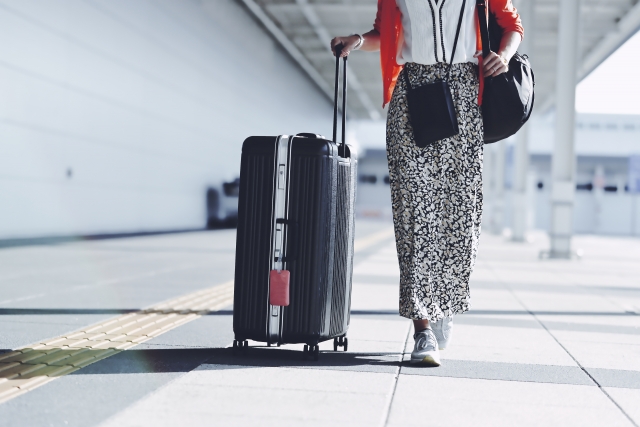 スーツケースをひきながら歩く女性。